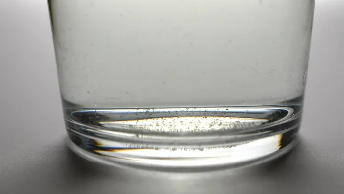 Glass of water with fine particles visible